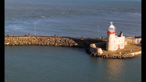 A-drone-reveal-shot-of-Howth-Harbour-lighthouse-and-Pier-in-the-evening-sunlight