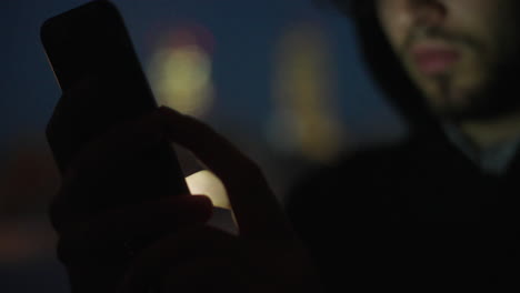 persona que utiliza un teléfono inteligente por la noche