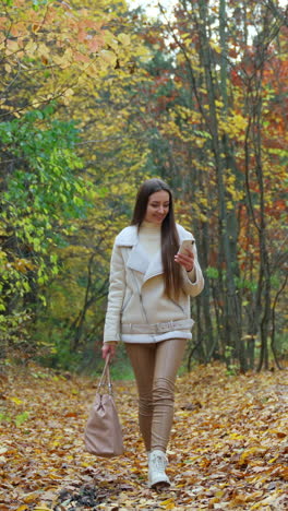 cheerful young lady in golden autumn park. lifestyle nature walking. vertical video