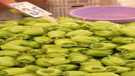 una pila de pimientos verdes en un mercado de agricultores