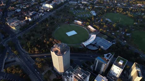 Apartment-blocks,-parks,-cricket-ground,-green-space,-aerial-tilt-down