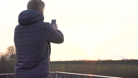 a person is taking photos with his phone while standing on a viewing platform