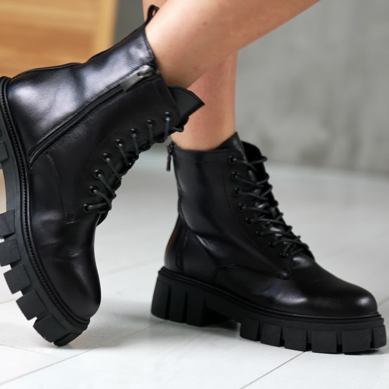 Female wearing the black low autumn boots with laces. Model turning in front of camera showing stylish footwear. Close up. White backdrop