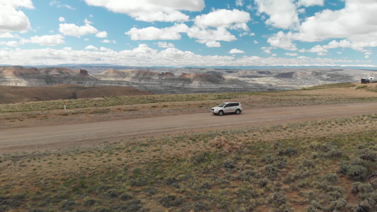 Órbita aérea y revelación de un coche en un camino de tierra en el Pilot Butte Wild Horse Scenic Loop, Wyoming, EE. UU.