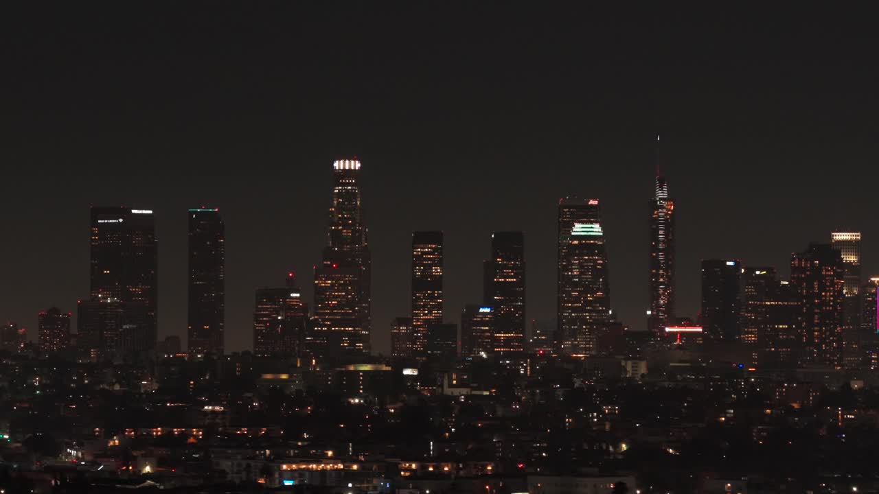 Aerial telephoto dolly shot of the downtown Los Angeles skyline at night in Southern California. 4K