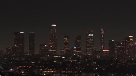 aerial telephoto dolly shot of the downtown los angeles skyline at night in southern california. 4k