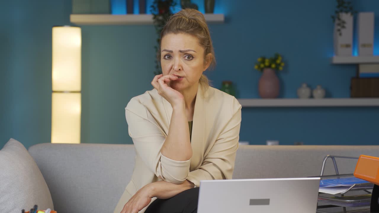 Home office worker woman biting her nails looking at camera.