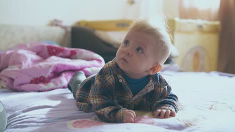 little baby in warm clothes lies on comfortable bed in room