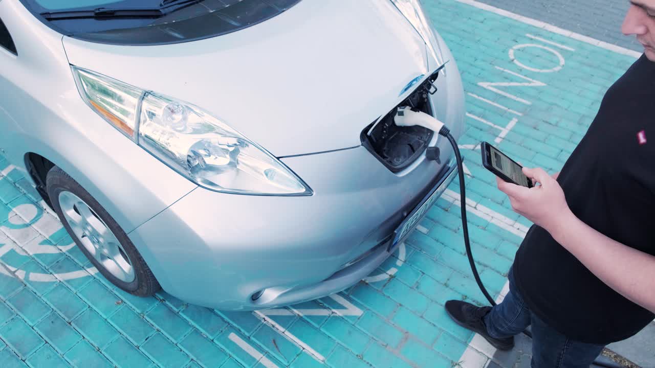 電気自動車の充電プロセス - 電気自動車が充電するハッチの下のショット - 電気車の充電ハッチは自動的に開きます - 男性の手が勃起した車を入します