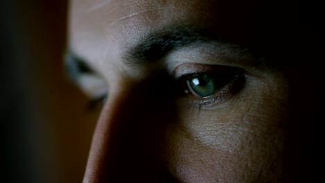 close-up of a green-blue man's eyes with screen reflecting in them.