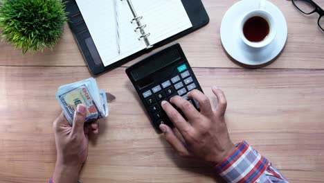 person calculating finances at a wooden desk