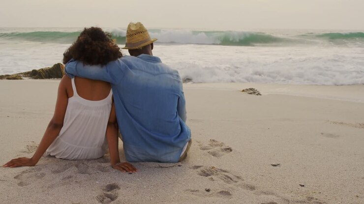 Vue arrière d'un couple afro-américain se relaxant ensemble sur la plage 4k