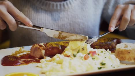 girl having german bratwurst sausage with ketchup and mashed potatoes, slow motion