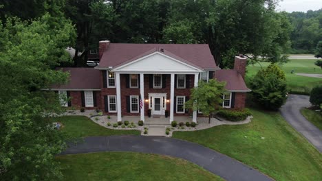 aerial drone footage drawing away from a large house in a luxury neighborhood at dusk