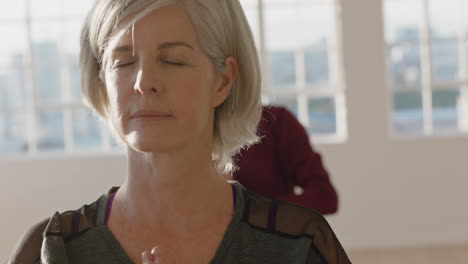 yoga class portrait of mature woman exercising healthy lifestyle practicing prayer pose enjoying group physical fitness workout in studio