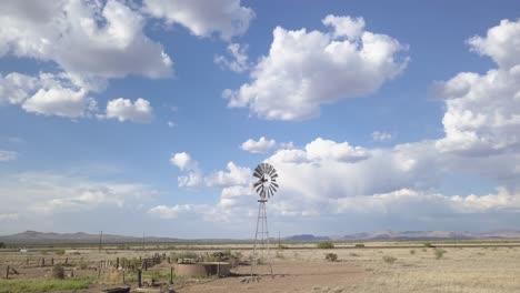 Drone-—-slowly-moving-across-the-landscape-with-windmill-and-massive-skies,-Texas