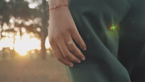 engagement in forest as woman walks through trees to beautiful sunset path