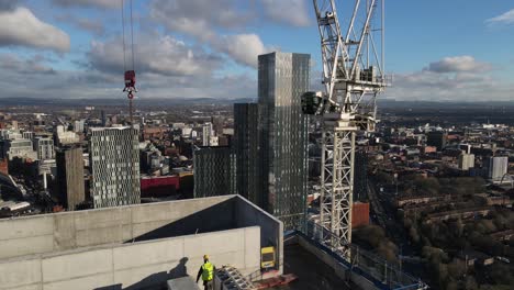 Aerial drone flight over a new Skyscraper under development on Deansgate in Manchester City Centre flying past a crane with a view of the South Towers in front and overlooking the rooftops below