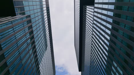 Upwards-abstract-dolly-view-of-shiny-exterior-of-skyscrapers-against-sky