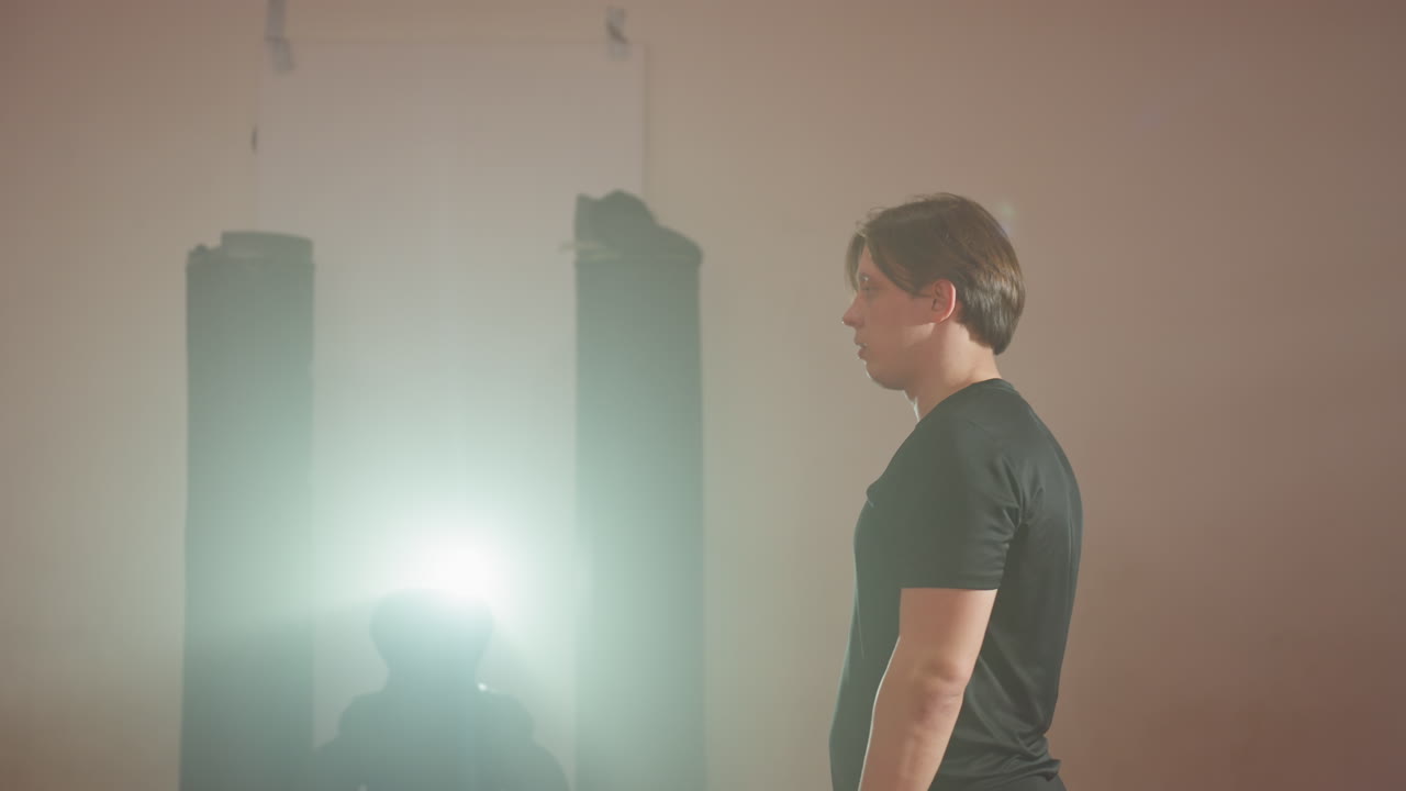 Karate practitioner executing acrobatic motion during martial arts training in gym, arms extended with intense movement, dynamic athletic performance on red mats, punching bags in background