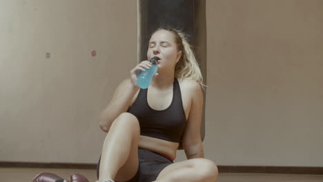 front view of exhausted athlete drinking isotonic in gym