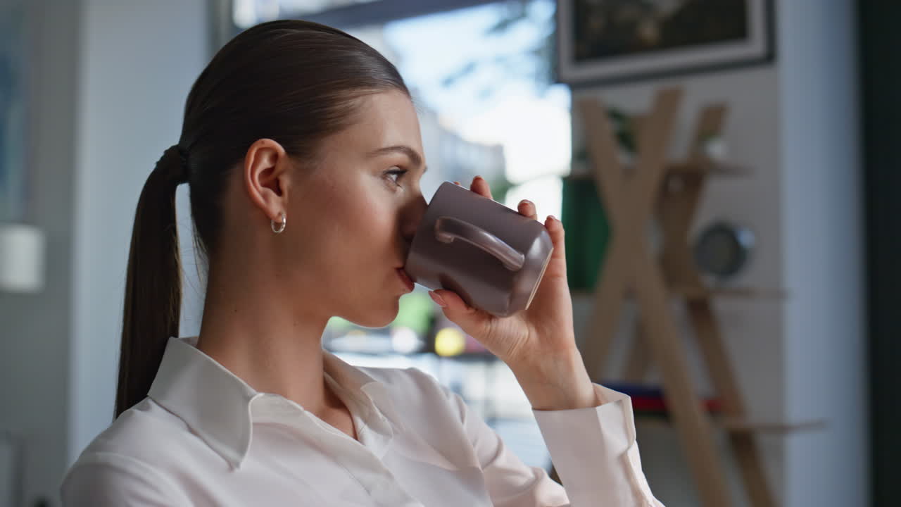 Calm employee sipping coffee enjoying work break in corporate office closeup