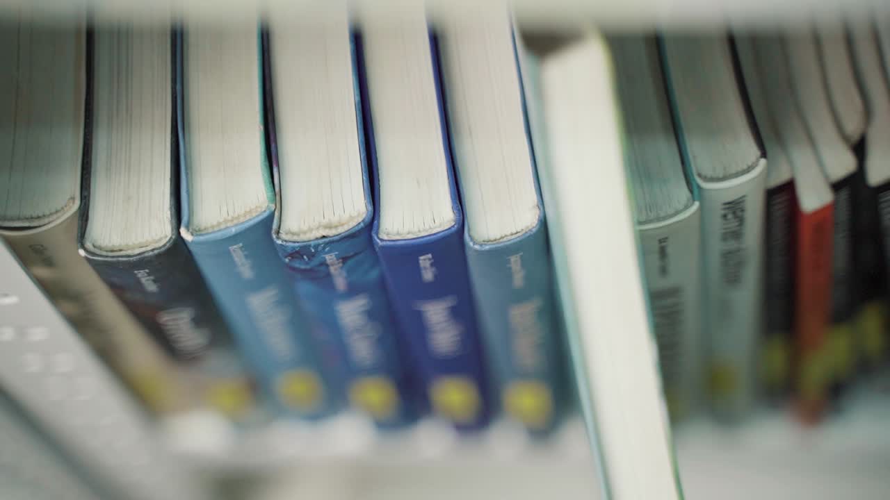 A hand moves finger along book spines until choosing on of the books
