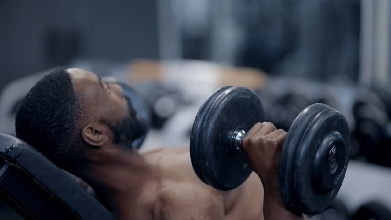 Atheltic African American man performs Dumbbell Press exercise