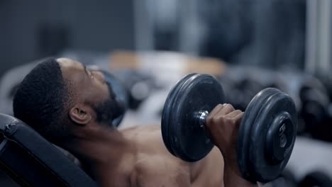 atheltic african american man performs dumbbell press exercise