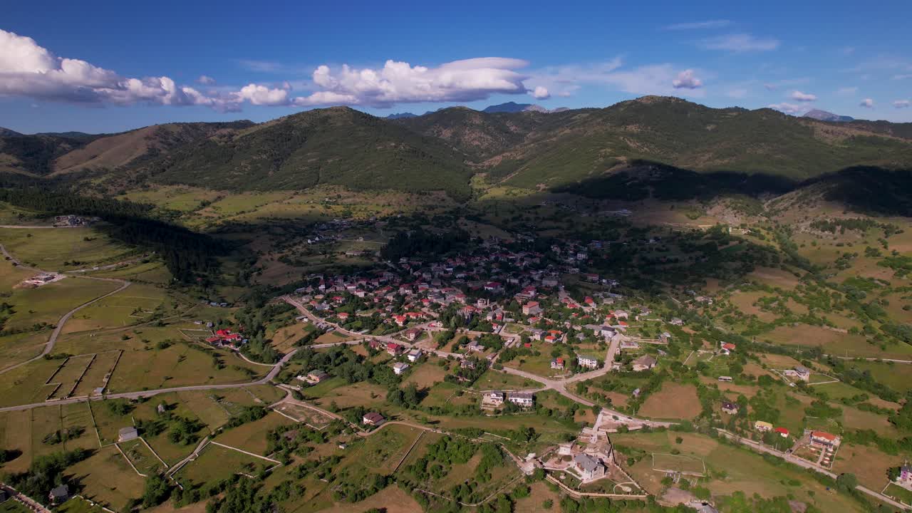 pueblo en medio de colinas y montañas cubiertas de verdes prados y bosques, albania