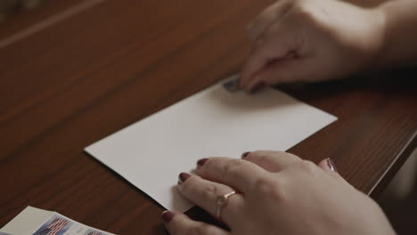 close up of a woman putting a stamp on an envelope