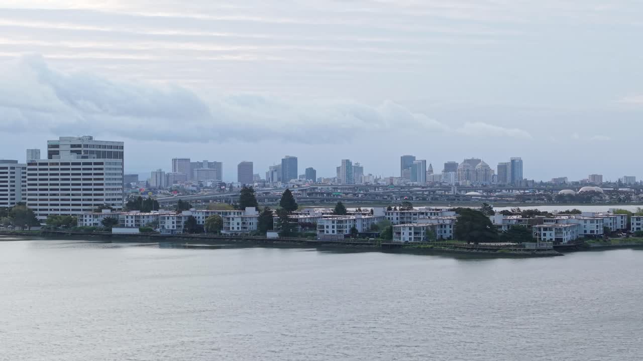 A sweeping drone view pans across Emeryville Marina Park, revealing sailboats, walking paths, and downtown Oakland in the distance.