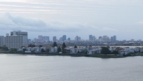 a sweeping drone view pans across emeryville marina park, revealing sailboats, walking paths, and downtown oakland in the distance.