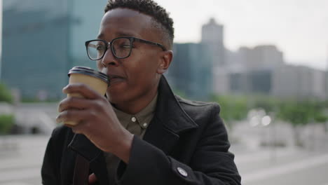 close up portrait of young trendy african american man student drinking coffee beverage in city relaxed wearing glasses