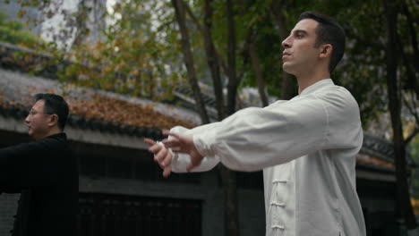 men practicing tai chi outdoors in a traditional setting