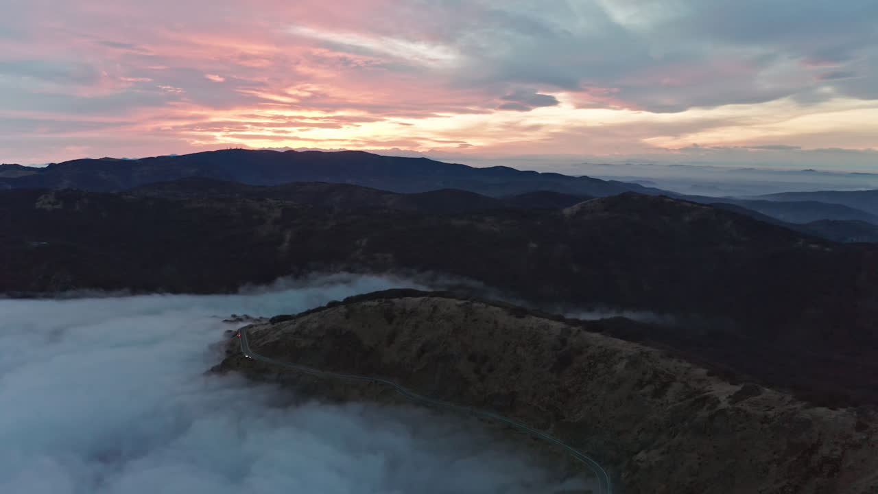 carreteras de montaña brumosas al amanecer con nubes suaves y luz suave, vista aérea