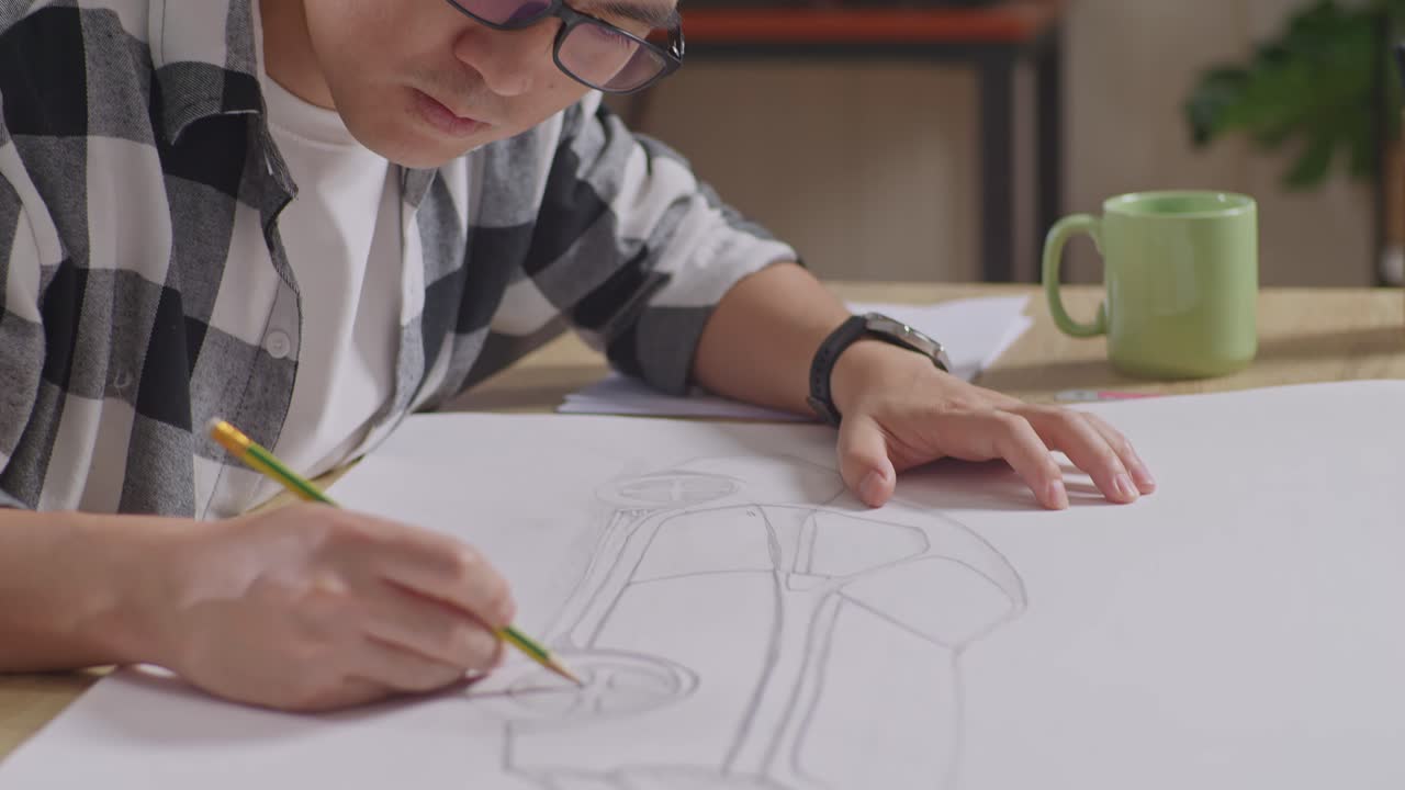 Close Up Of Asian Male Working On A Paper About Car Design Sketch On Table In The Studio