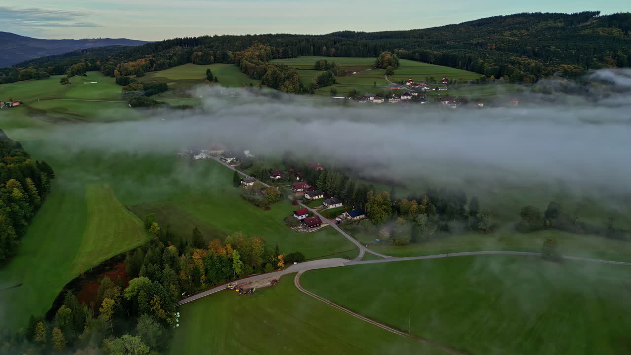 drone aéreo hacia adelante disparado sobre un pequeño pueblo sobre la ladera de la montaña en un día nublado