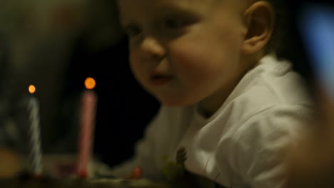 niño soplando dos velas en su pastel de cumpleaños