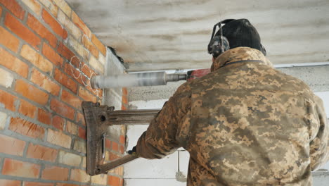 constructor perfora un agujero en la pared de ladrillo con una potente herramienta eléctrica