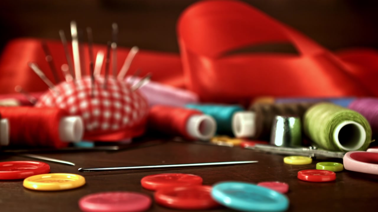 Slow Motion Sewing Needle Falling onto a Table with Craft Supplies