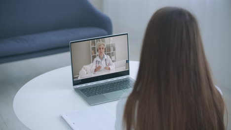 Shoulder-view-young-woman-consulting-with-family-therapist-doctor-general-practitioner-online-via-video-call-on-laptop-after-feeling-first-virus-illness-symptoms-medical-insurance-covid19-outspread.