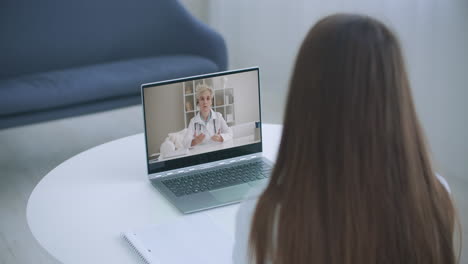 una mujer joven consulta con un terapeuta familiar, un médico generalista en línea a través de una llamada de video en una computadora portátil después de sentir los primeros síntomas de enfermedad por virus.