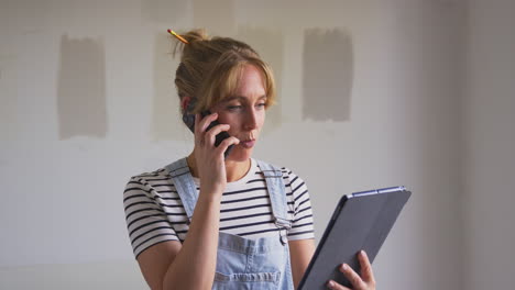 mujer decorando una habitación en la casa haciendo una llamada telefónica mirando una tableta digital con tiras de prueba de pintura