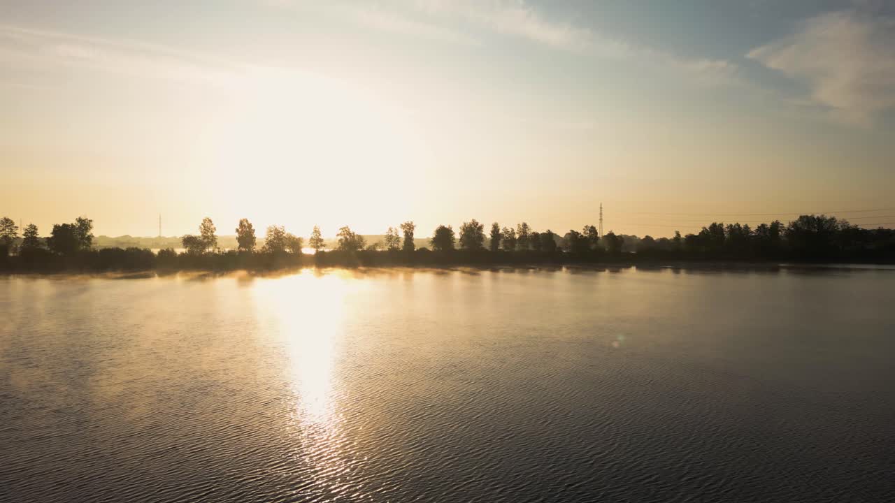 안개 가 가득 한 해변 에 있는 조용 한 호수 위 의 해가 뜨는 것