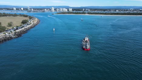 large sand dredging ship positioned in the middle of a popular city harbor for coastal replenishment projects