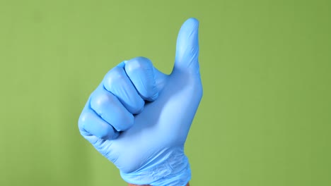 close-up of a person hand in medical gloves showing a thumb-up.