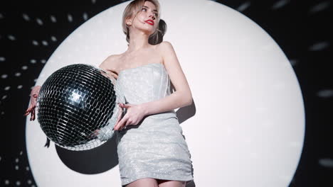 vrouw in een zilveren jurk met een disco bal
