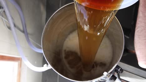 Slow-motion-top-shot-of-man-pouring-beer-into-fermenter-to-start-the-fermenting-process