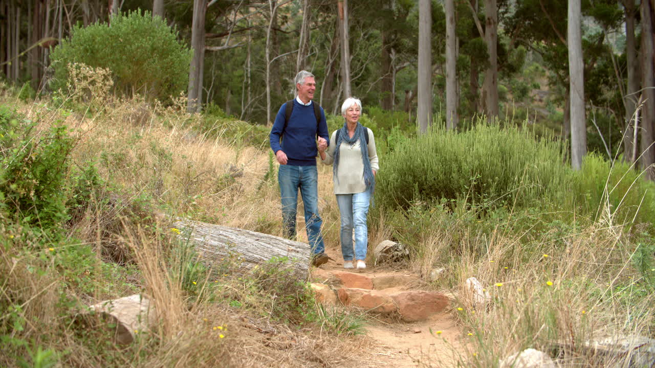 una pareja de ancianos caminando hacia la cámara en un camino rural